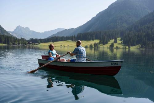 a man and woman in a boat on a lake at LA SOA Chalets & Eventlodge in Schattwald