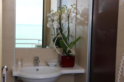 un lavabo con un jarrón de flores. en Hotel Metropol en Pesaro