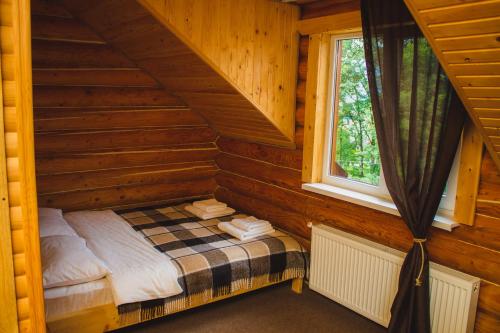 Cama pequeña en una cabaña de madera con ventana en Guest House Svitliza, en Yaremche