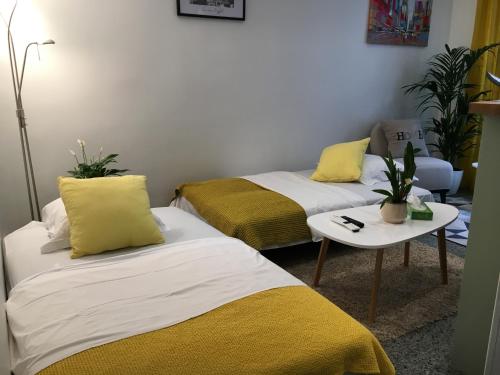Cette chambre comprend 2 lits avec des oreillers jaunes et une table. dans l'établissement Paris City Flat App entier N106 F3, à Paris