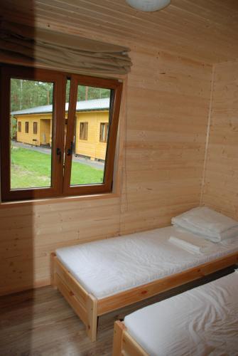 Cabaña de madera con 2 camas y ventana en AURUM Domki Letniskowe, en Pogorzelica