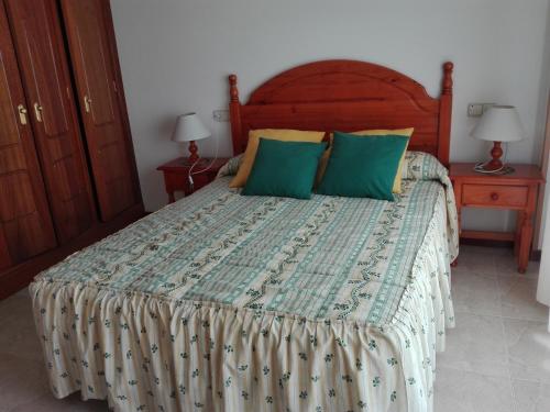 ein Schlafzimmer mit einem großen Bett mit grünen Kissen in der Unterkunft Apartamentos Esther in Sanxenxo
