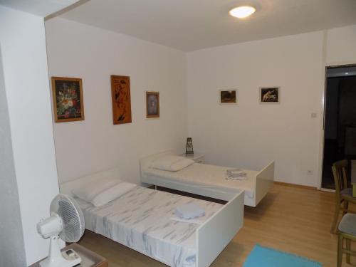Jest to biały pokój z 2 łóżkami i wentylatorem. w obiekcie Borovik Guest House w mieście Živogošće
