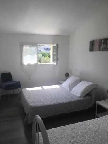 ein weißes Schlafzimmer mit einem Bett und einem Fenster in der Unterkunft Villa Mer Et Montagne in Macinaggio
