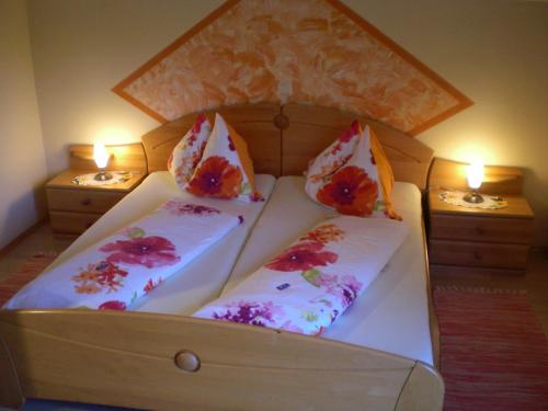 a bed with three pillows on it with two lights at Pension Thermensonne in Jennersdorf