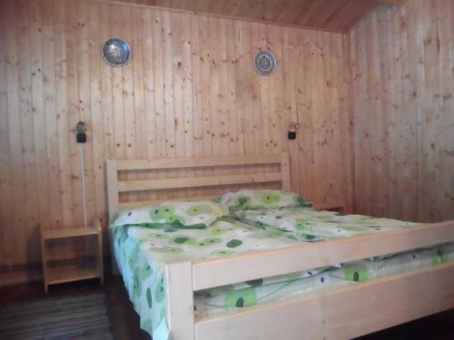 a wooden bed in a room with wooden walls at Casutele Likas in Lacu Rosu