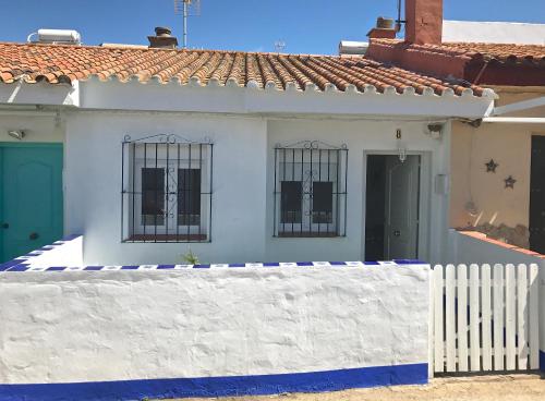 ein weißes Haus mit vergitterten Fenstern und einem weißen Zaun in der Unterkunft Sol de Bolonia 8 in Bolonia