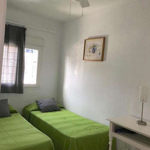 two green beds in a room with a window at Casa Azul in Bolonia