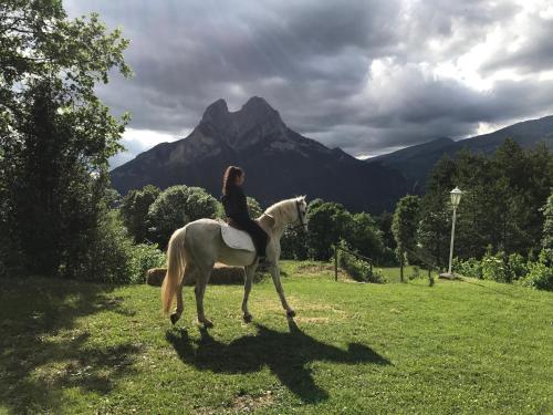 a woman riding a white horse in a field at Hostal Pedraforca in Saldés