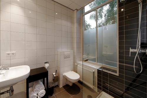 a bathroom with a toilet and a sink and a shower at Hotel De Villa in Dongen