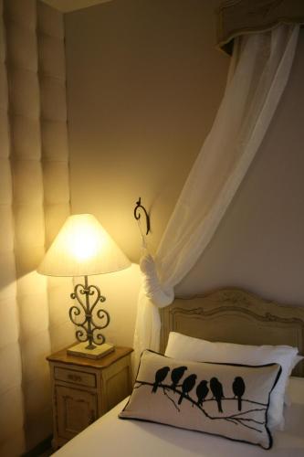 a bedroom with a bed with a canopy with birds on the pillow at Le Prieuré Chambres d'hôtes in Sainte-Preuve