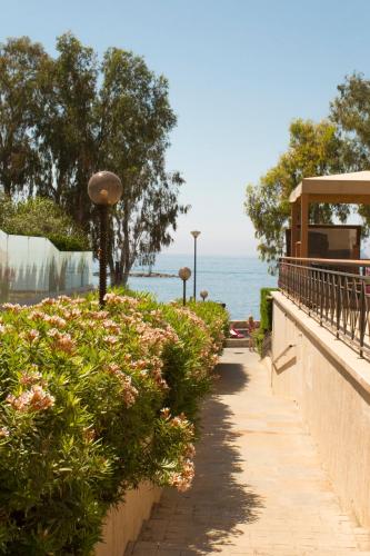 a walkway next to the ocean with flowers at Galatex Beach Apartment in Limassol