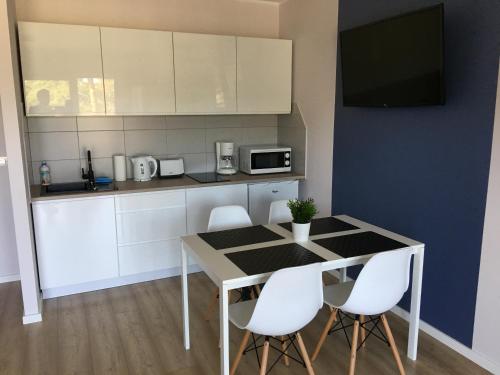 a kitchen with a table and chairs and a tv at Apartament Silver in Pogorzelica