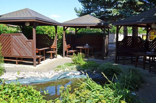a garden with tables and chairs and a pond at Hotel U Racka in Ostrožská Nová Ves