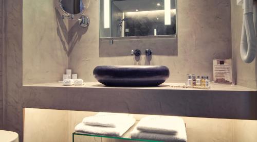 a bathroom with a sink and a mirror and towels at SAZ City Life Boutique Hotel in Ioannina
