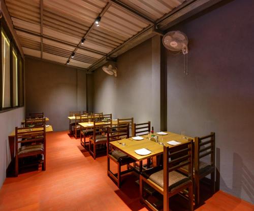 Un comedor con mesas y sillas de madera. en Hotel Shree Sai, en Kolhapur