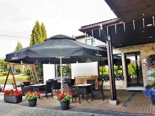een patio met een parasol en tafels en stoelen bij Hotel Barka in Kalwaria Zebrzydowska