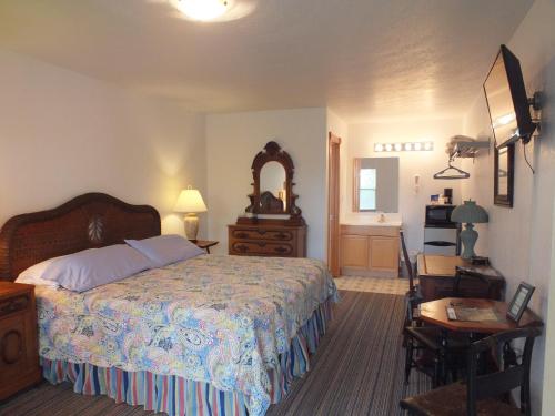 a bedroom with a bed and a table and a mirror at Scarborough Inn in Manteo