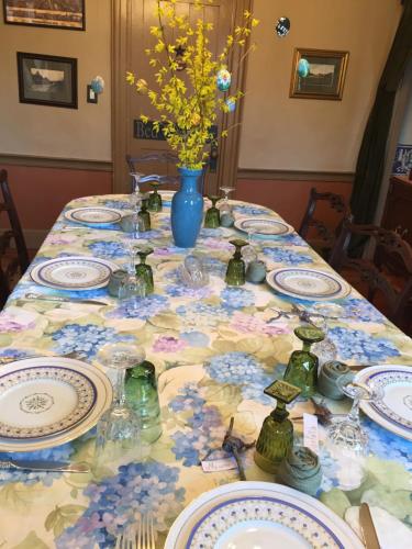 a table with plates and a vase with flowers on it at Innkeeper's Place B&B in Stafford Springs