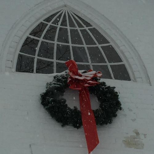 a christmas wreath with a red bow in front of a window at Innkeeper's Place B&B in Stafford Springs