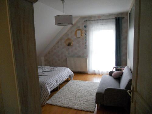 a bedroom with a bed and a window and a couch at Si le coeur vous en dit in Châtenois