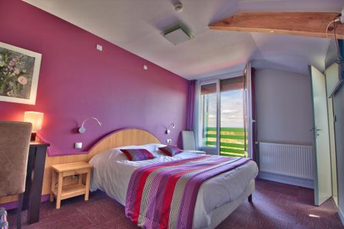 a bedroom with a bed with a purple wall at Logis Hôtel Restaurant Le Chalet du Mont Roland in Dole