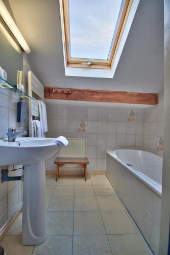 a bathroom with a sink and a tub and a skylight at Logis Hôtel Restaurant Le Chalet du Mont Roland in Dole