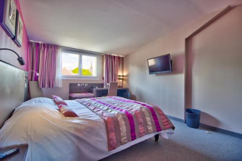 a bedroom with a bed and a window and a tv at Logis Hôtel Restaurant Le Chalet du Mont Roland in Dole