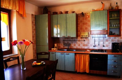 una cucina con armadi verdi e un tavolo con un vaso di fiori di Casa Vacanze L'Agrifoglio a Montefalcione