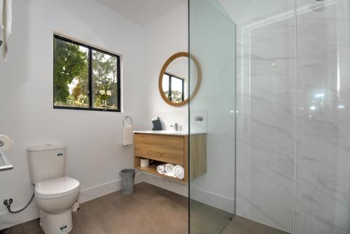 a bathroom with a toilet and a glass shower at Eumundi Cottages - Cottage 1 in Eumundi