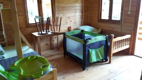 a room in a log cabin with a crib and windows at Słoneczna Polana in Solina