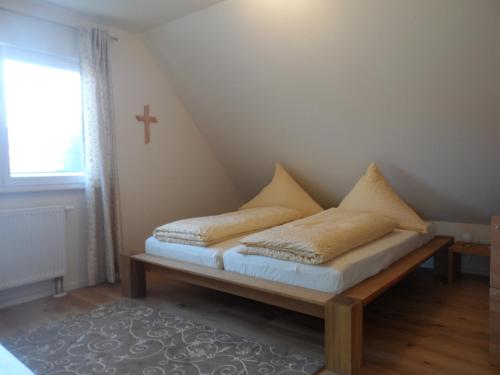a bed in a room with a cross on the wall at Pension am Kirschgarten in Gößweinstein