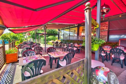 a restaurant with tables and chairs under a red roof at Logis Hôtel Restaurant Le Chalet du Mont Roland in Dole