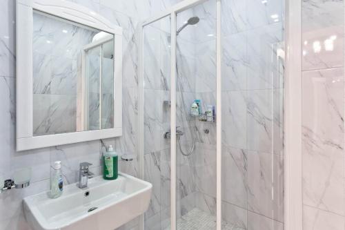 a white bathroom with a sink and a shower at Cozy Apartments in Arcadia in Odesa