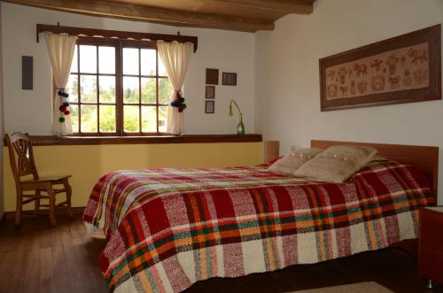 a bedroom with a bed with a colorful blanket and a window at FUENTE FLORES -Casa de campo- in Iza