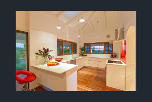 a large kitchen with white counters and a red stool at Eumundi Mountain Retreat in Eumundi