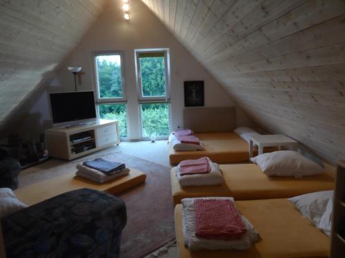 a attic room with four beds and a television at Pension am Kirschgarten in Gößweinstein