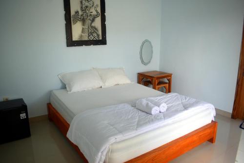 a bedroom with a bed with white sheets and a mirror at Wani Bali Resort in Nusa Penida
