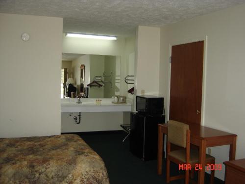 een hotelkamer met een bed, een bureau en een wastafel bij Homegate Inn in Louisville