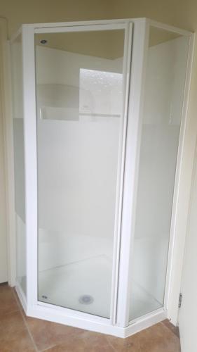 a white cabinet with glass doors in a room at Hot Water Beach Cottage in Hotwater Beach