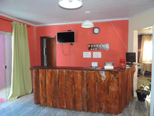 a room with a wooden counter with a tv on a red wall at Pousada Centaurus in Alto Paraíso de Goiás