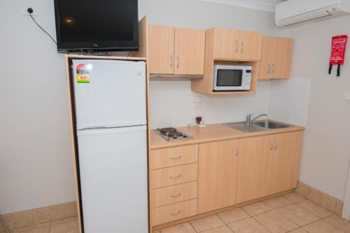 
a kitchen with a refrigerator, microwave, sink, and dishwasher at Ningaloo Reef Resort in Coral Bay
