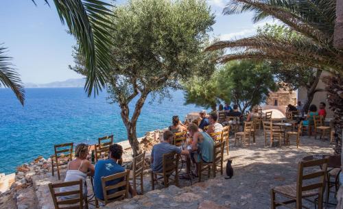 a group of people sitting at a table by the water at Bastione Malvasia Hotel (ex New Malvasia) in Monemvasia