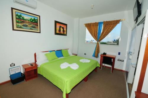 een slaapkamer met een groen bed en een raam bij Isla Azul in Puerto Ayora