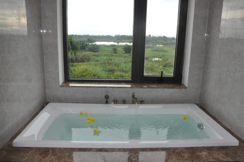 a bath tub with flowers in it with a window at The Quin Riverside Villa in Hoi An