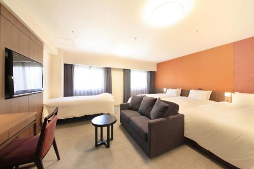 a hotel room with two beds and a couch at Richmond Hotel Kagoshima Kinseicho in Kagoshima