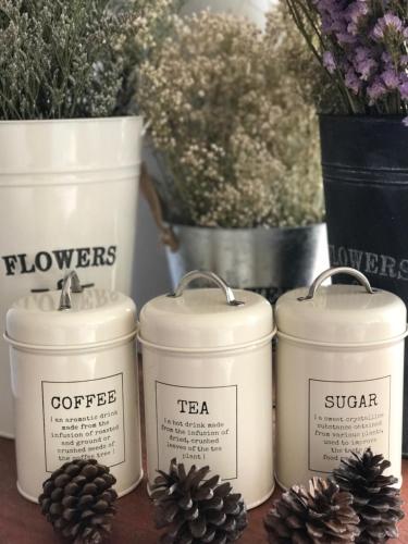a group of four white canisters on a table with pine cones at De Nan Hotel in Nan
