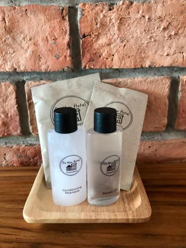 two bottles of shampoo sitting on a wooden cutting board at De Nan Hotel in Nan