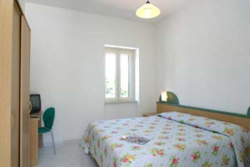 a bedroom with a bed and a desk and a window at La Collinetta in Peschici