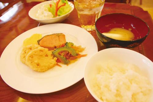 a table with two plates of food and a bowl of rice at Hotel Sun Queen in Naha